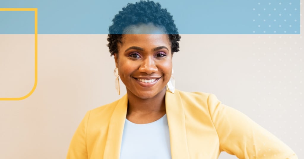 Adult woman standing in a pale yellow blazer and smiling.