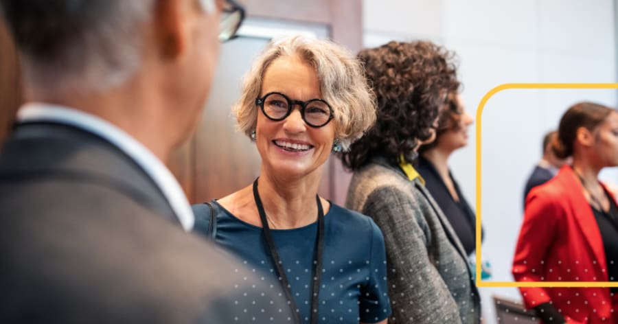 A woman with round glasses is smiling.