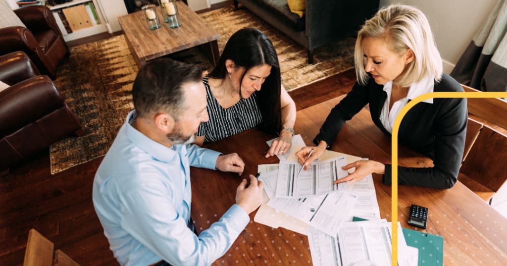 Three professionals sitting at a desk reviewing documents.