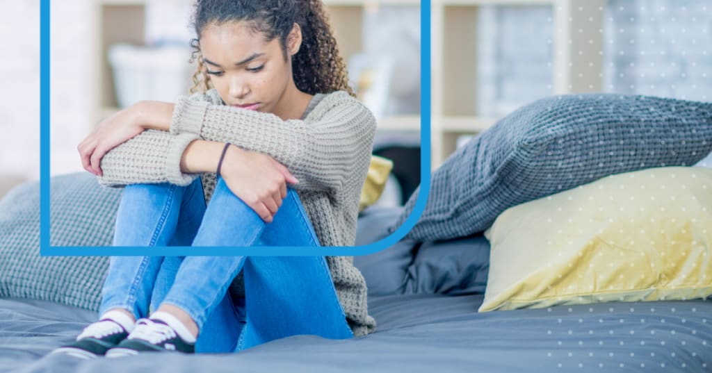 Sad looking teen hugging their knees.