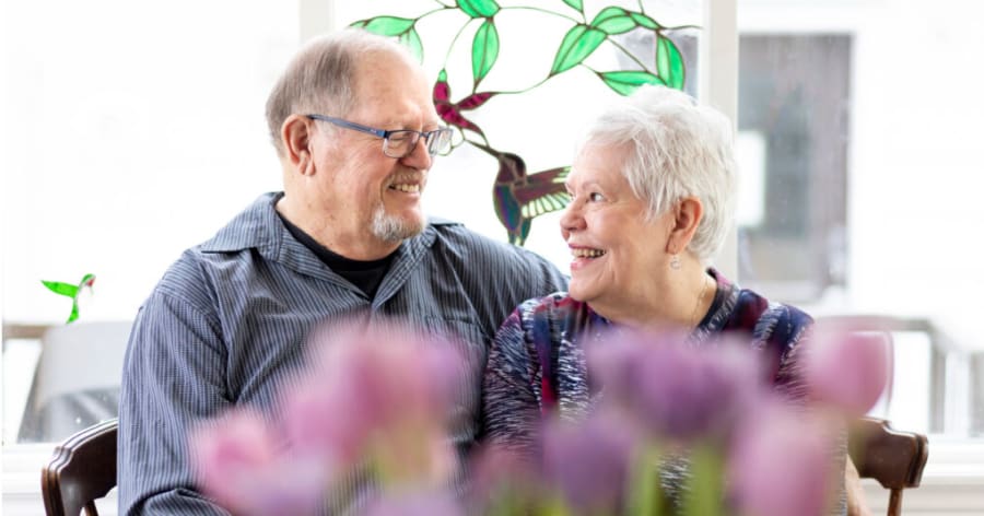 A senior couple is looking at each other and smiling.