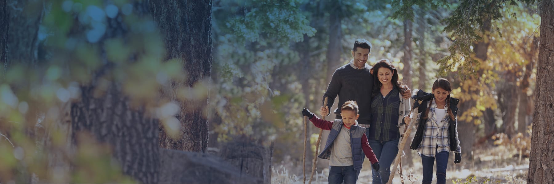 A family walks outside in a wooded area.